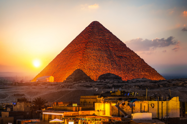 The Pyramids of Giza at sunset with a camel silhouette in the foreground